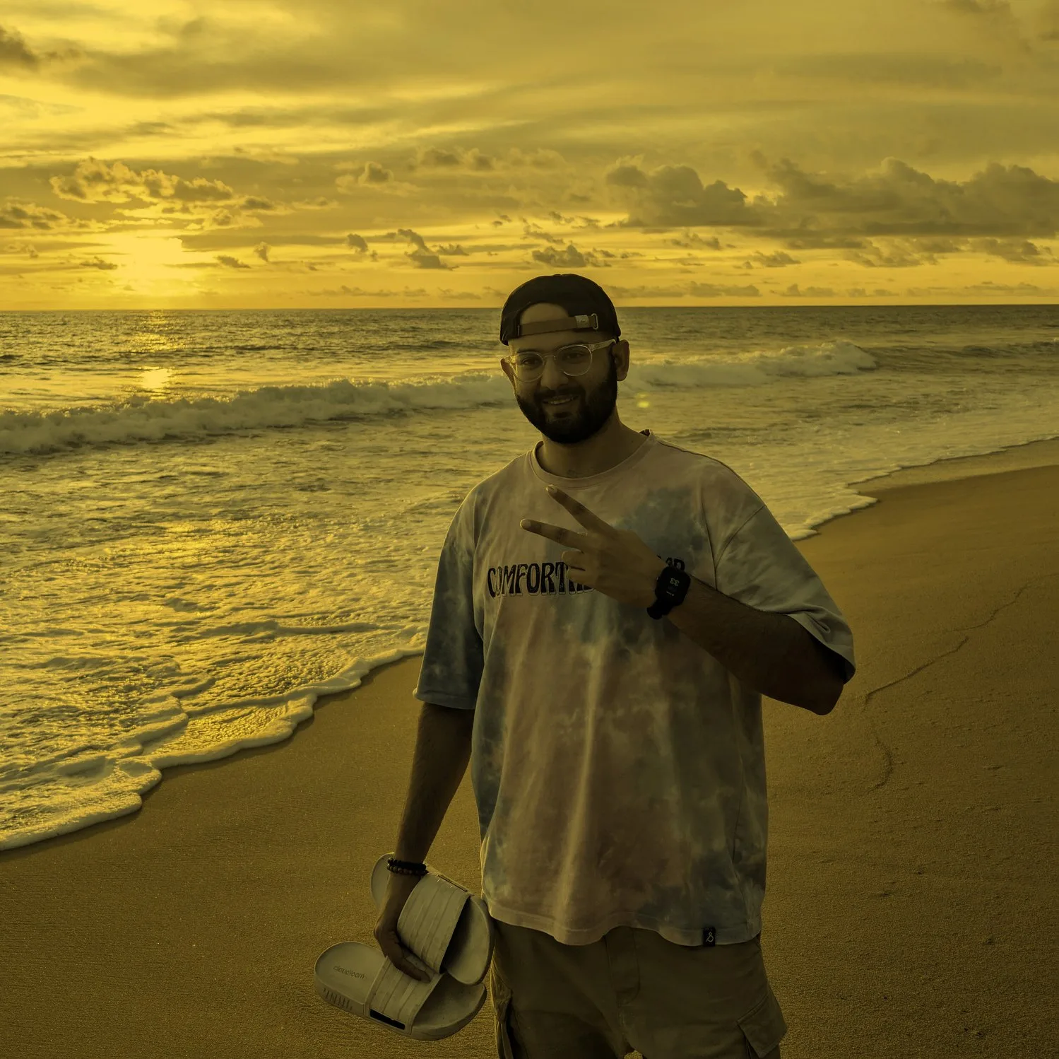 Ramit Sharan on a beach at sunset, making a peace sign