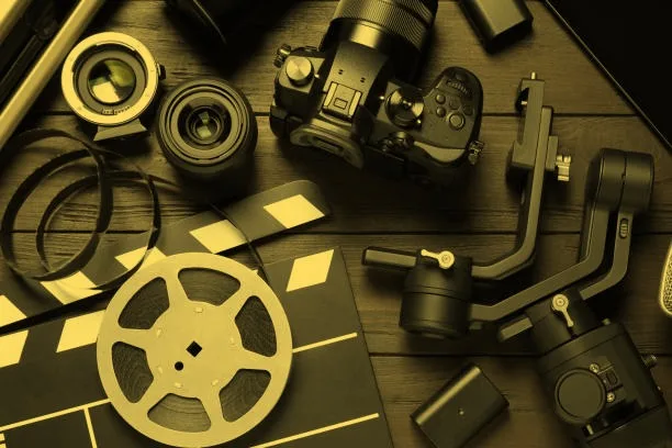 Film-making gear laid out on a table: camera, lenses, gimbal, film reel and clapperboard